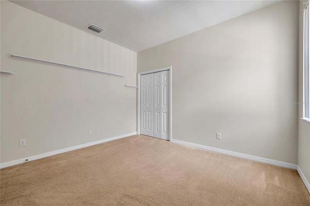 carpeted empty room featuring baseboards and visible vents