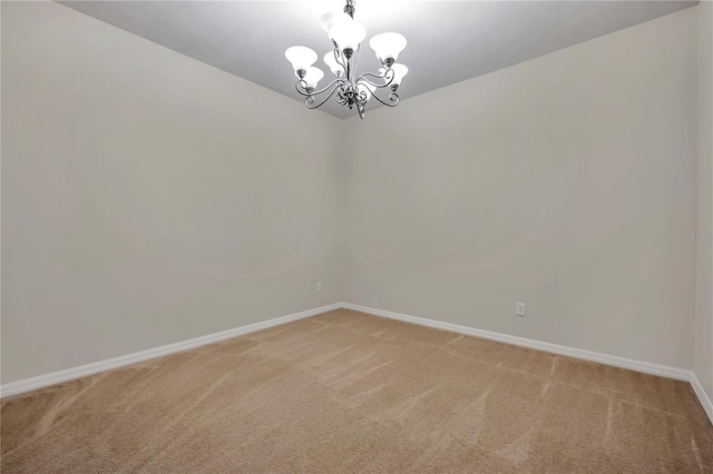 empty room featuring baseboards, light carpet, and a chandelier