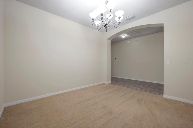 empty room featuring visible vents, light carpet, baseboards, a chandelier, and arched walkways