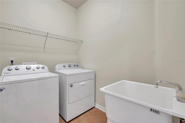 laundry room featuring light tile patterned flooring, laundry area, a sink, baseboards, and washer and clothes dryer