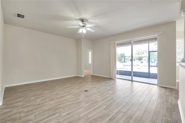 empty room featuring baseboards, ceiling fan, light wood finished floors, and visible vents