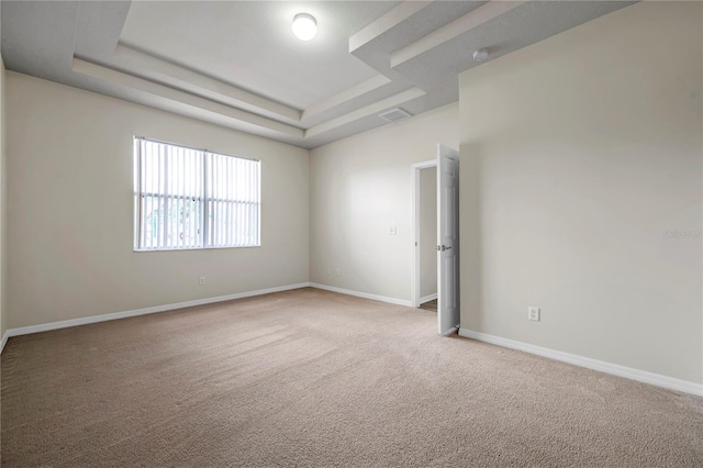 unfurnished room with visible vents, a raised ceiling, carpet floors, and baseboards