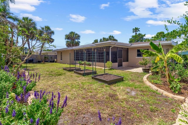 4340 50th Ter S, Saint Petersburg, FL 33711 - back of house with a sunroom, a vegetable garden, fence, a yard, and concrete block siding