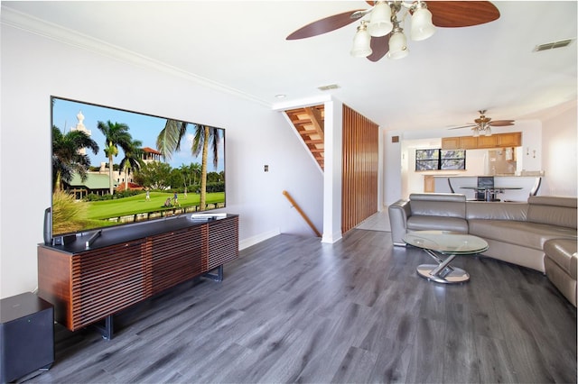 living area with ceiling fan, stairs, wood finished floors, baseboards, and crown molding