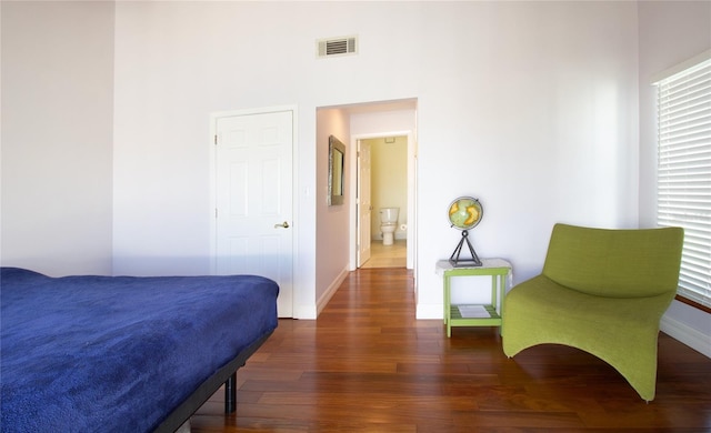 bedroom featuring wood finished floors, baseboards, and a towering ceiling