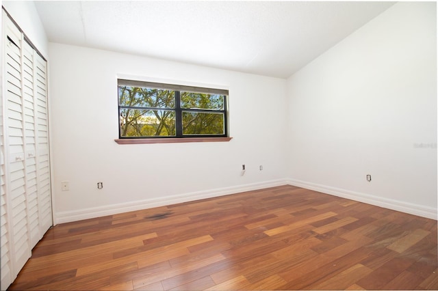 unfurnished bedroom with wood finished floors, baseboards, and a closet