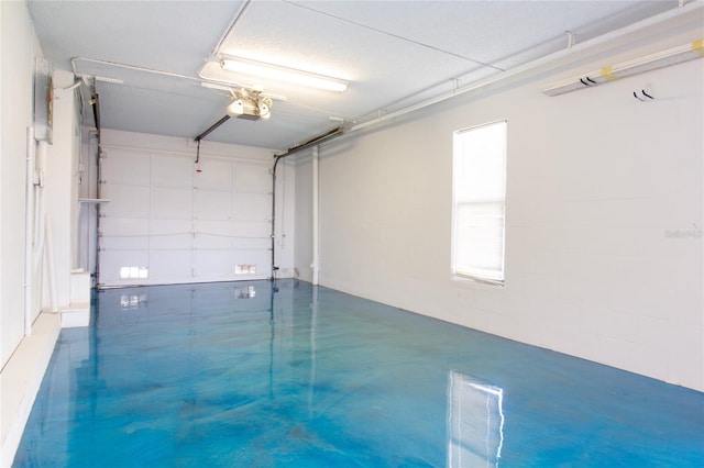 garage with a garage door opener and concrete block wall