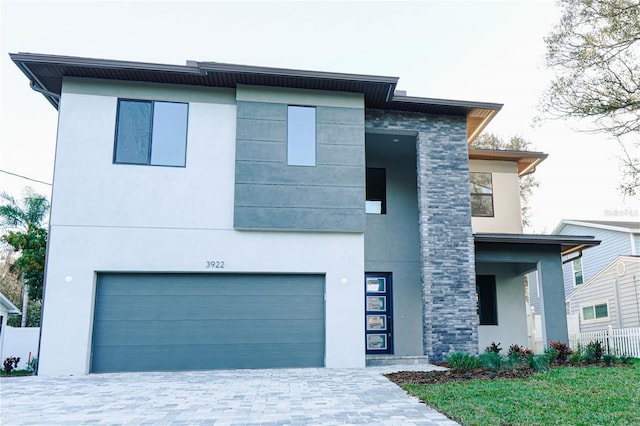 3310 W Rogers Ave, Tampa, FL 33611 - contemporary home featuring an attached garage, stucco siding, decorative driveway, and stone siding