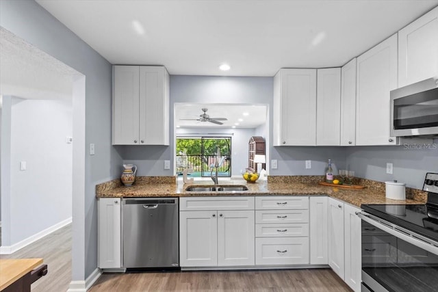 3600 Magnolia Ridge Cir Unit 1221-G, Palm Harbor, FL 34684 - kitchen featuring dark stone counters, white cabinetry, a sink, appliances with stainless steel finishes, and light wood-style floors