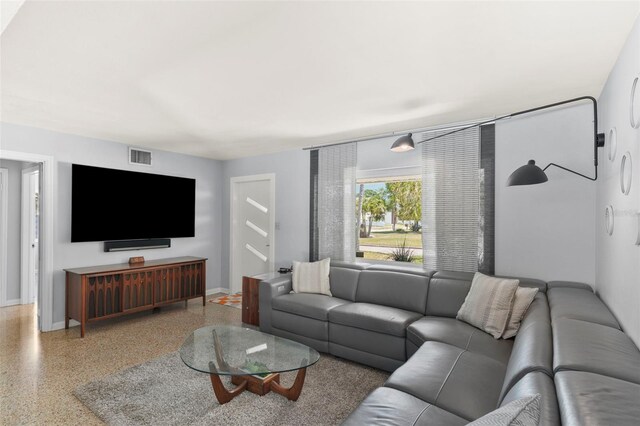 living room with baseboards, visible vents, and speckled floor