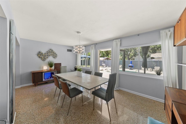 dining area with an inviting chandelier, visible vents, speckled floor, and baseboards