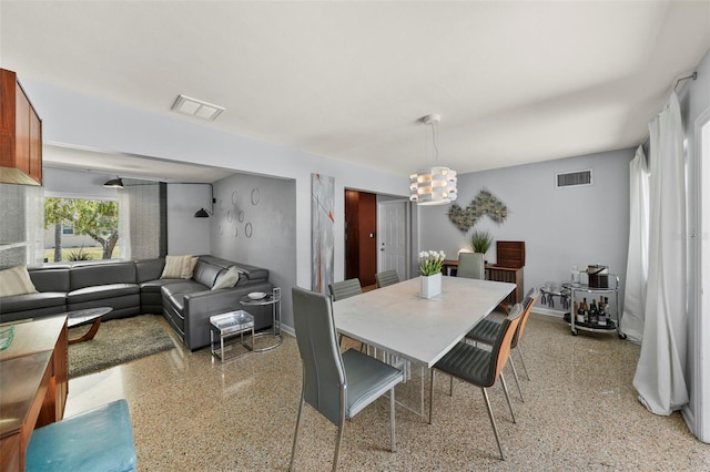 dining area with light speckled floor, an inviting chandelier, visible vents, and baseboards