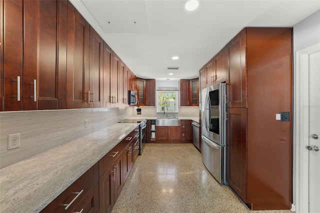 kitchen with a sink, glass insert cabinets, visible vents, backsplash, and appliances with stainless steel finishes
