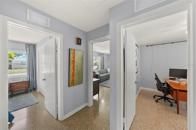 interior space featuring baseboards, visible vents, and speckled floor
