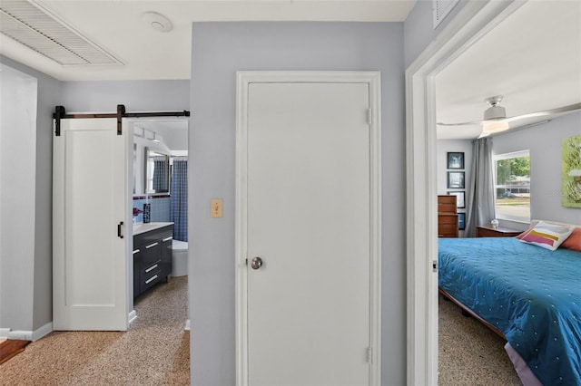 bedroom featuring a barn door, baseboards, and light speckled floor