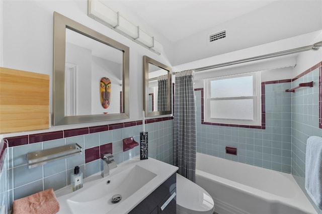 bathroom with tile walls, shower / bathtub combination with curtain, toilet, vanity, and visible vents