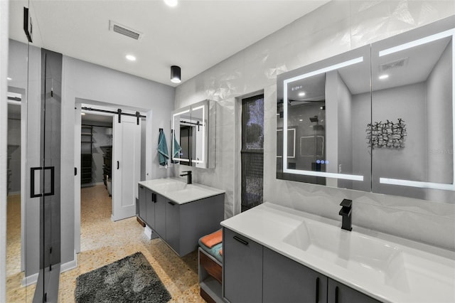 full bath with a sink, a shower stall, visible vents, and speckled floor