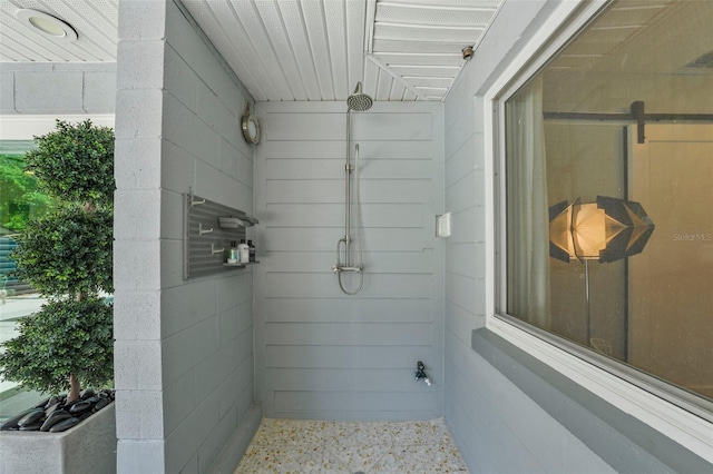 bathroom with a tile shower and speckled floor