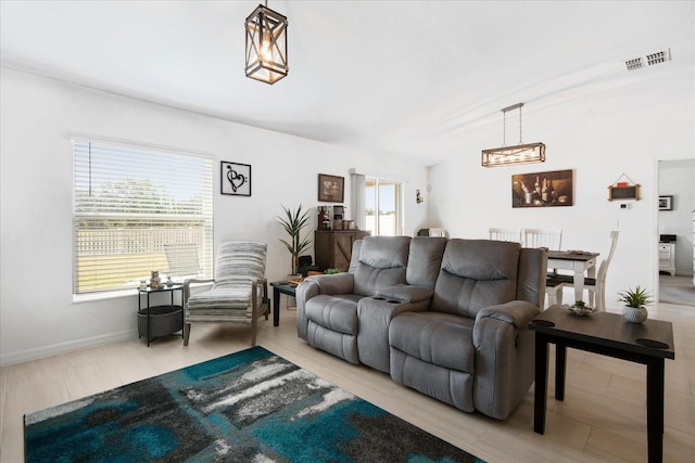 living room with wood finished floors, visible vents, a healthy amount of sunlight, and baseboards
