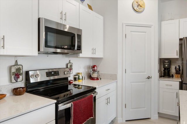 kitchen with appliances with stainless steel finishes, white cabinetry, and light stone countertops