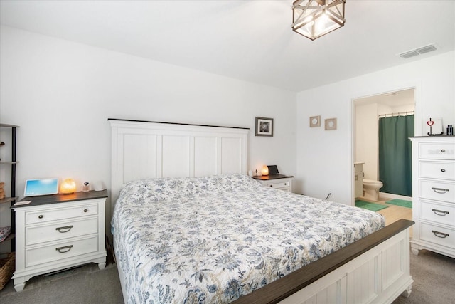bedroom featuring visible vents, dark colored carpet, and ensuite bathroom