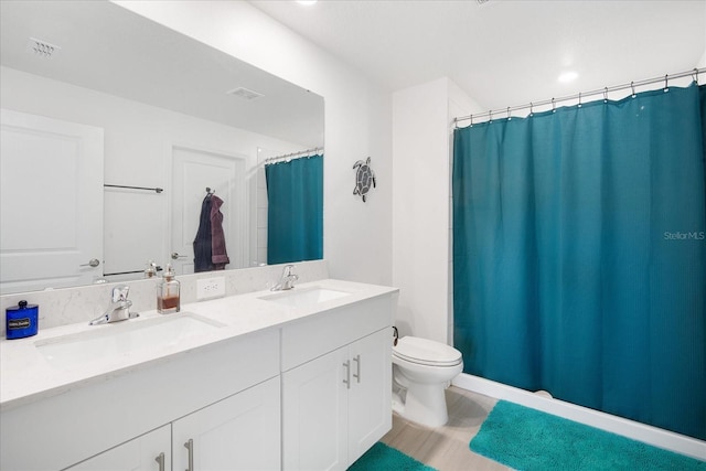 bathroom featuring double vanity, visible vents, toilet, and a sink