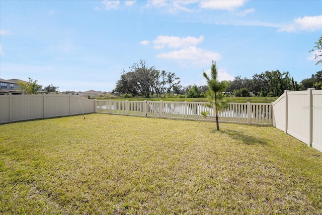 view of yard with a fenced backyard and a water view