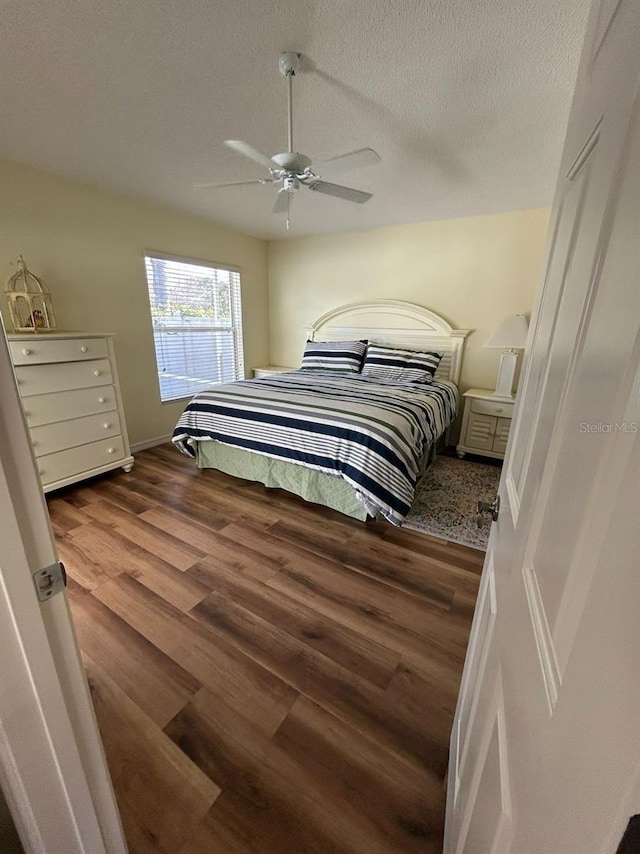 bedroom featuring a textured ceiling, ceiling fan, wood finished floors, and baseboards