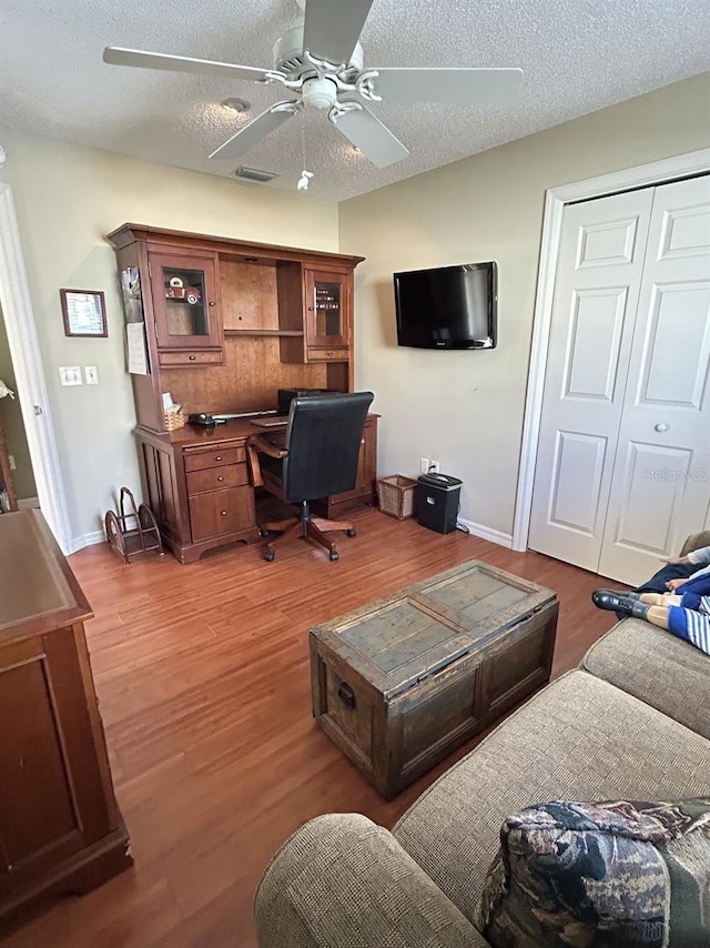 office with ceiling fan, visible vents, baseboards, a textured ceiling, and wood finished floors