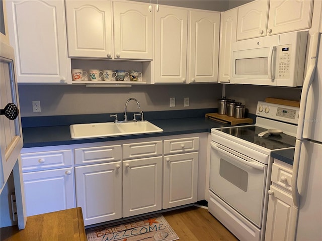 8320 112th St Unit 206, Seminole, FL 33772 - kitchen with dark countertops, white cabinetry, a sink, and white appliances