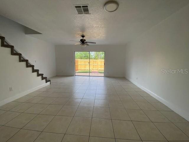 13909 Fletchers Mill Dr, Tampa, FL 33613 - empty room featuring ceiling fan, light tile patterned floors, stairway, baseboards, and a textured ceiling