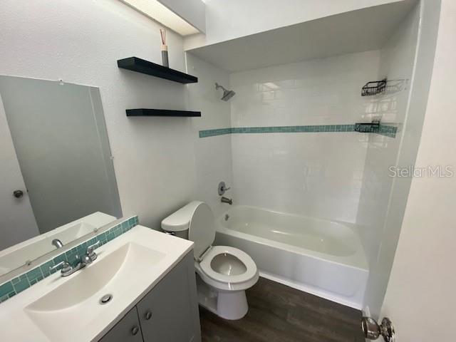 13909 Fletchers Mill Dr, Tampa, FL 33613 - bathroom featuring toilet, wood finished floors, washtub / shower combination, and vanity