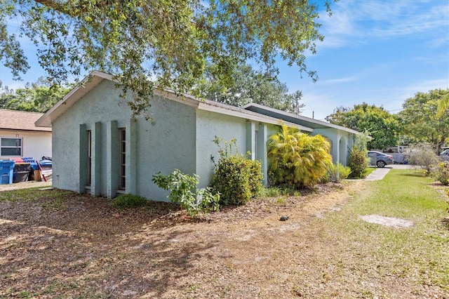 view of side of property with stucco siding and a yard