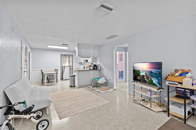 living room with visible vents, a textured ceiling, and speckled floor