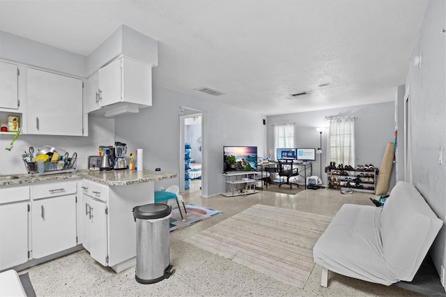 kitchen with light speckled floor, open floor plan, visible vents, white cabinetry, and light countertops