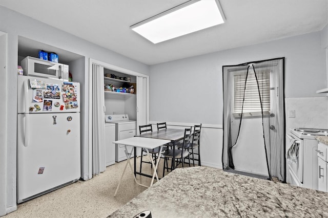 kitchen featuring light speckled floor, white appliances, washer and dryer, and white cabinetry