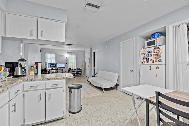 kitchen featuring light speckled floor, visible vents, white cabinetry, and white appliances