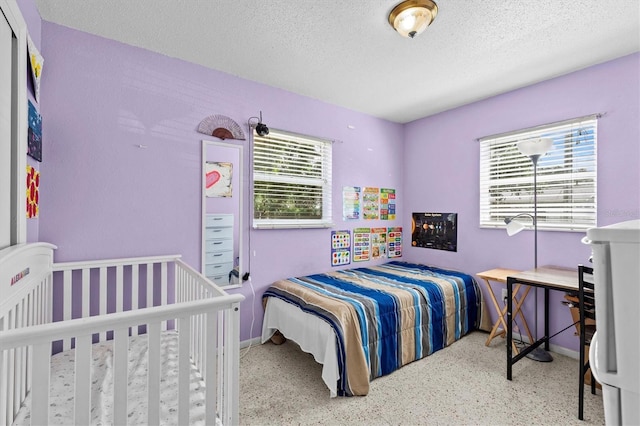 bedroom with speckled floor, a textured ceiling, baseboards, and multiple windows