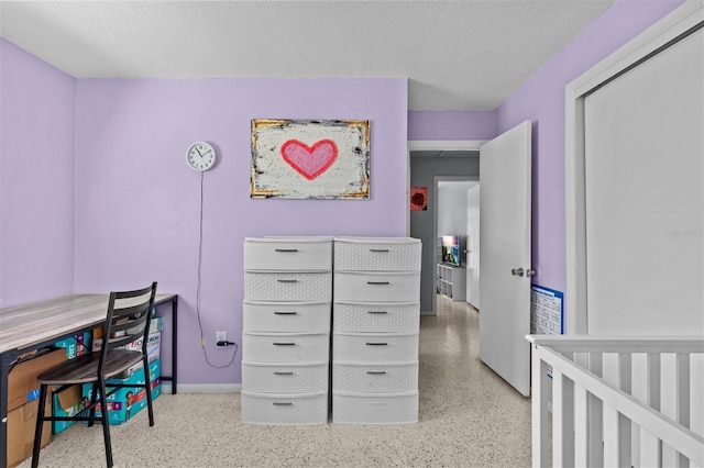 bedroom featuring speckled floor, a textured ceiling, and baseboards