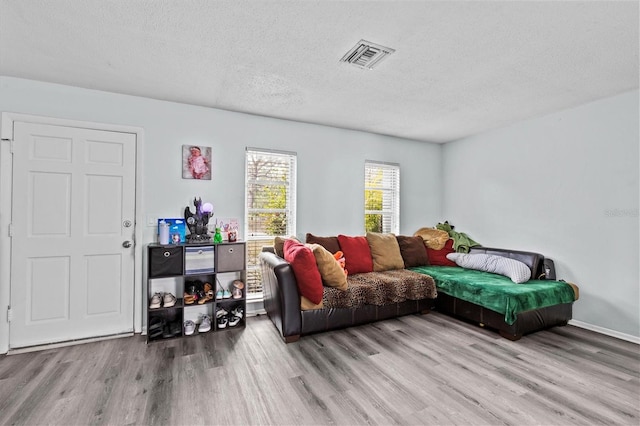 living room featuring wood finished floors, visible vents, and a textured ceiling