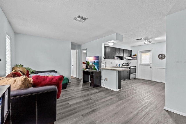 kitchen featuring open floor plan, wood finished floors, visible vents, and stainless steel range with electric stovetop