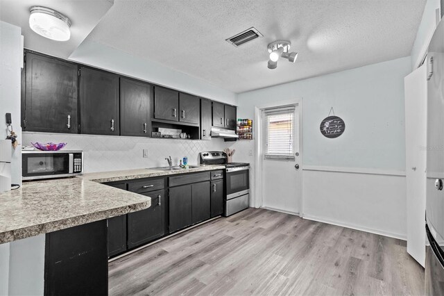 kitchen with dark cabinets, appliances with stainless steel finishes, a sink, and visible vents