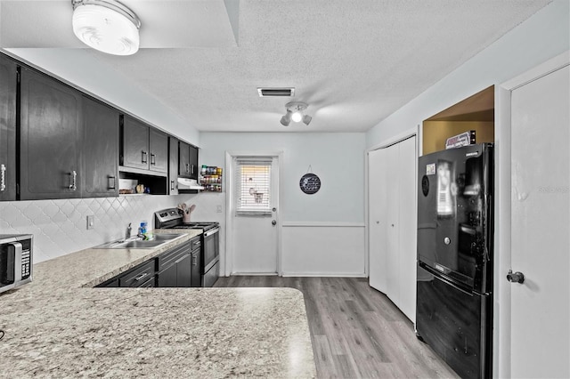 kitchen featuring stainless steel appliances, light countertops, visible vents, a sink, and light wood-style floors