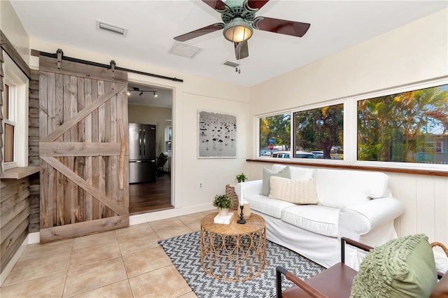 1419 55th St S, Gulfport, FL 33707 - living room with a barn door, tile patterned flooring, a ceiling fan, and baseboards