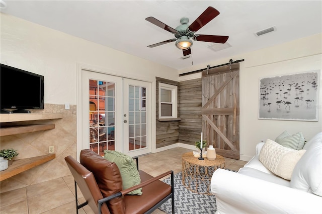 1419 55th St S, Gulfport, FL 33707 - living room featuring a barn door, tile patterned flooring, ceiling fan, and french doors