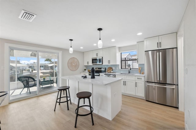 13810 Malcolm Ave, Hudson, FL 34667 - kitchen featuring appliances with stainless steel finishes, a sink, white cabinetry, a center island, and backsplash