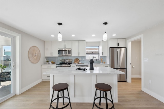 13810 Malcolm Ave, Hudson, FL 34667 - kitchen featuring appliances with stainless steel finishes, a breakfast bar, decorative backsplash, a kitchen island, and baseboards