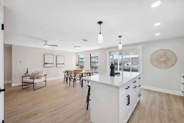 13810 Malcolm Ave, Hudson, FL 34667 - kitchen with baseboards, light wood finished floors, white cabinetry, hanging light fixtures, and a breakfast bar area