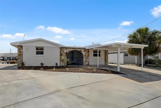 13810 Malcolm Ave, Hudson, FL 34667 - view of front of property with stone siding, concrete driveway, a carport, and stucco siding