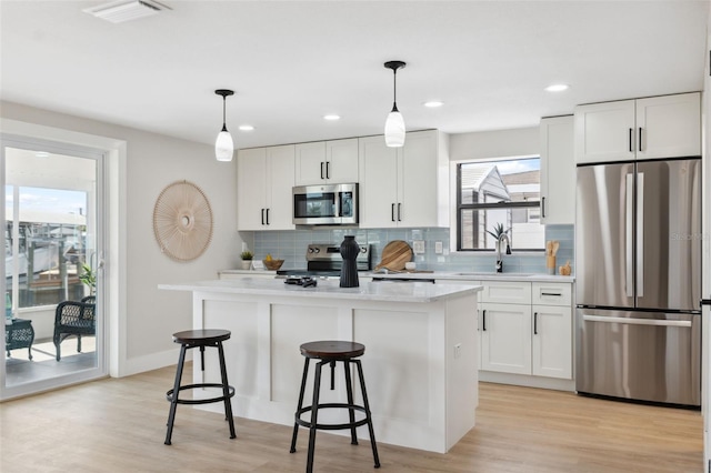 13810 Malcolm Ave, Hudson, FL 34667 - kitchen with stainless steel appliances, a sink, a kitchen island, backsplash, and white cabinetry